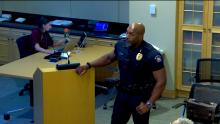 Aurora Police Officer standing at a podium and the image links to the Council Study Session from June 24 2024